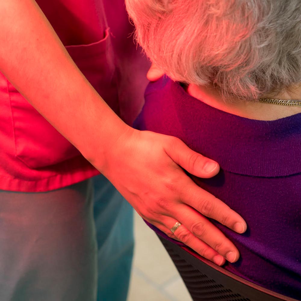 Una trabajadora apoya su mano en la espalda de una residente