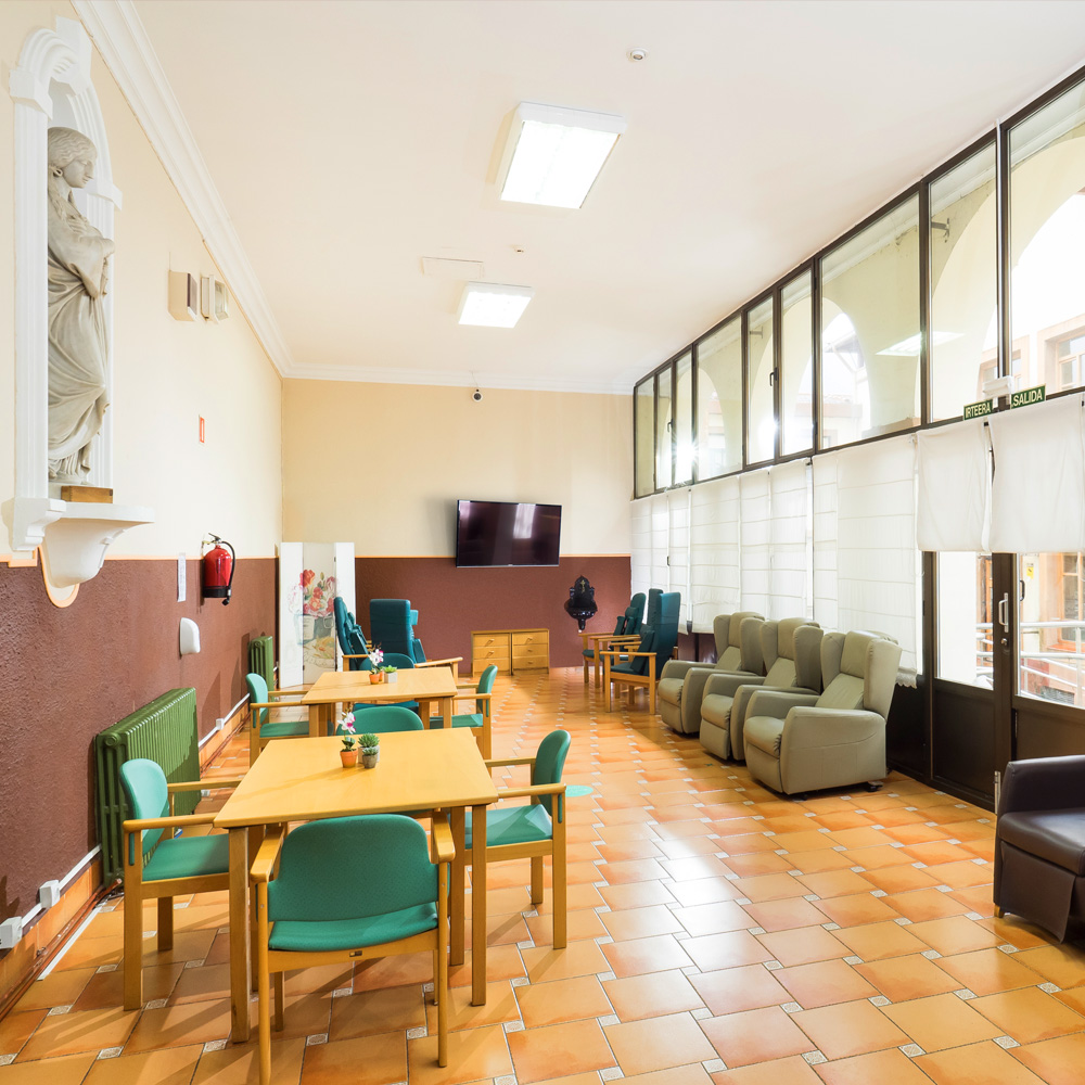 Una de las salas comunes de la residencia de mayores León Trucíos con sillas, mesas butacas y televisión