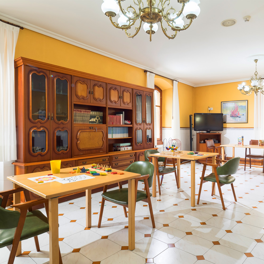 Sala de terapia ocupacional de la residencia de mayores León Trucíos con varias mesas, sillas y piezas para talleres